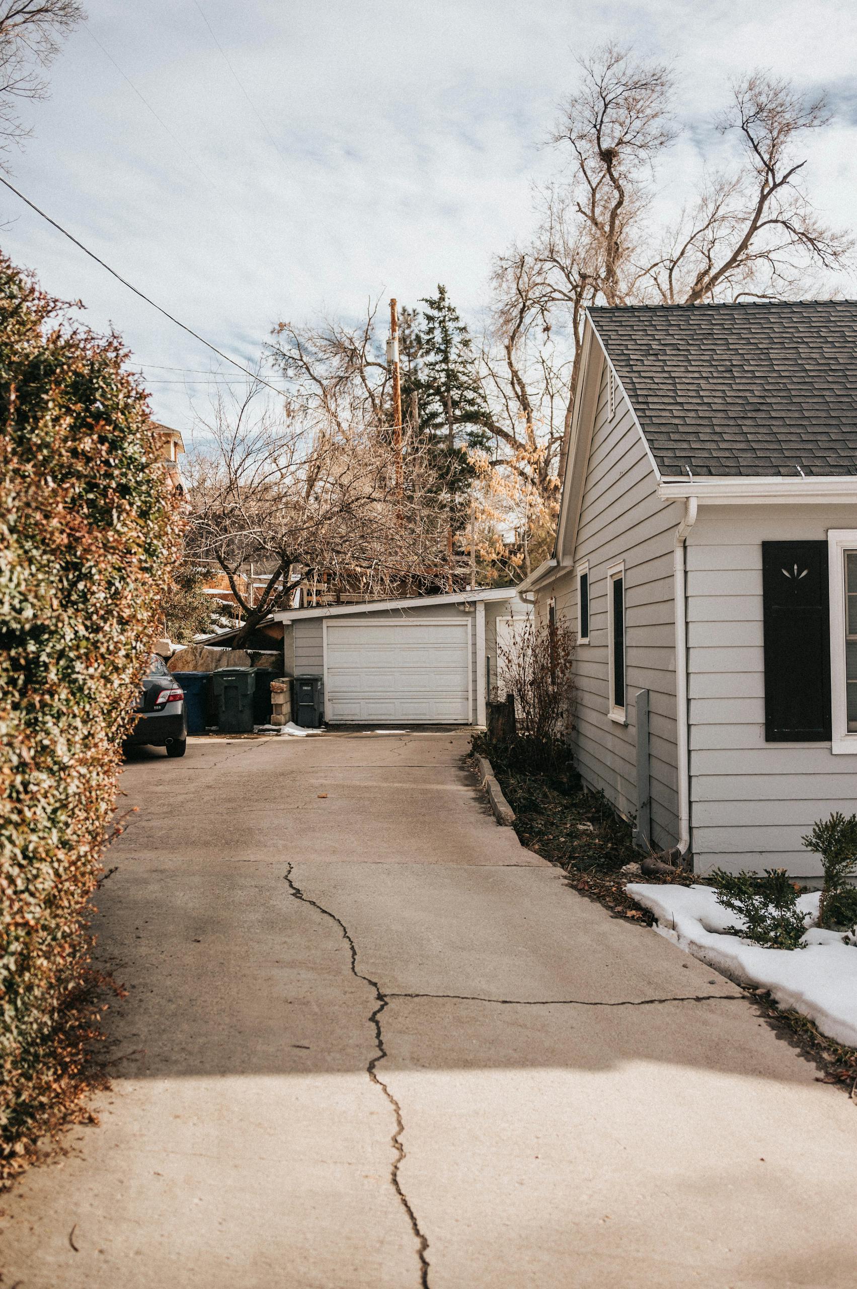 Old Home A Peaceful Suburban Driveway With Cracked Pavement Leading To A House Surrounded By Bare Trees 15913566 Scaled 1